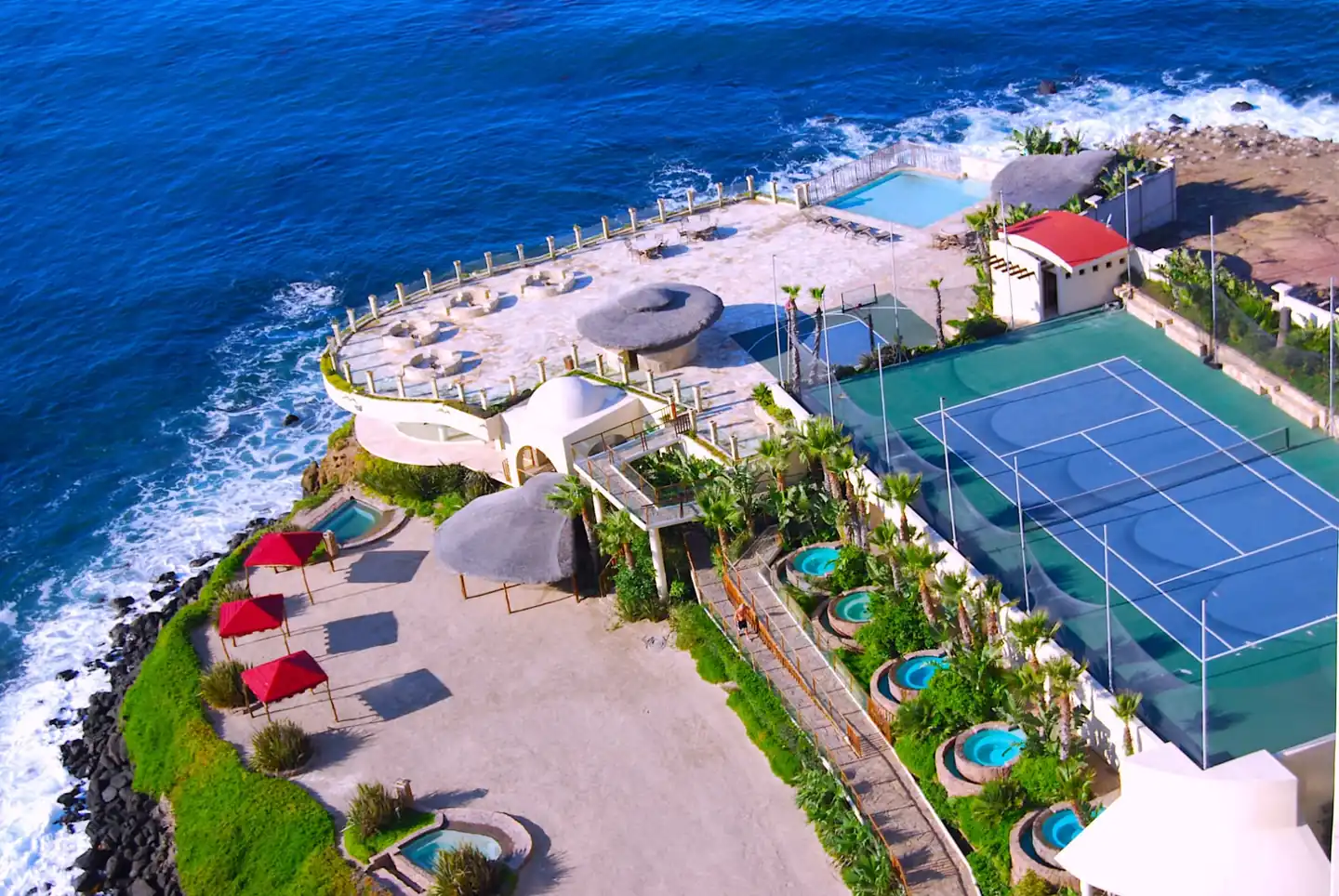 Bird's-eye view of the Holistic Sanctuary terraces, jacuzzis, beach and tennis court above the Pacific