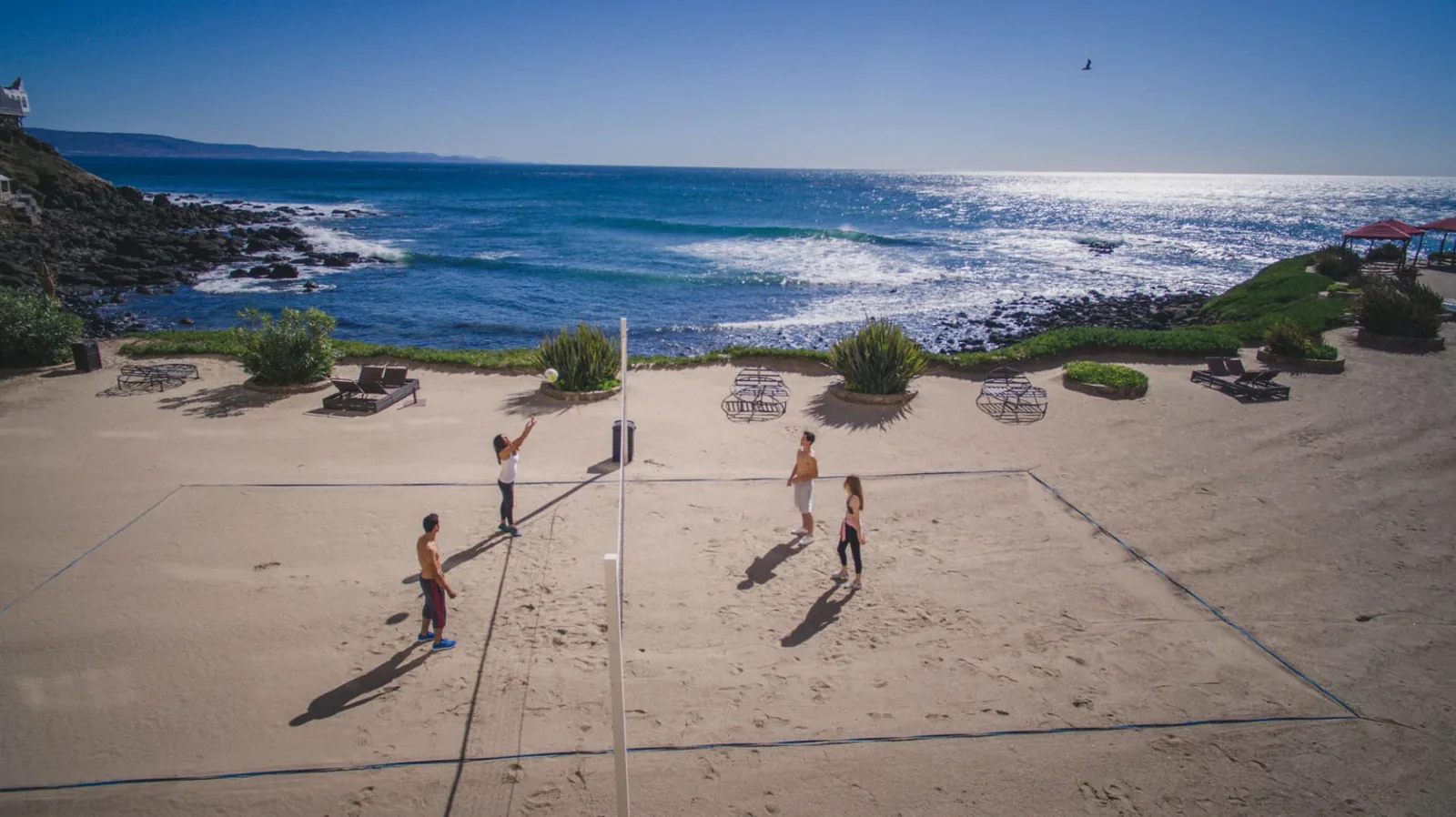 Four residents playing volleyball on the private beach court beside the ocean