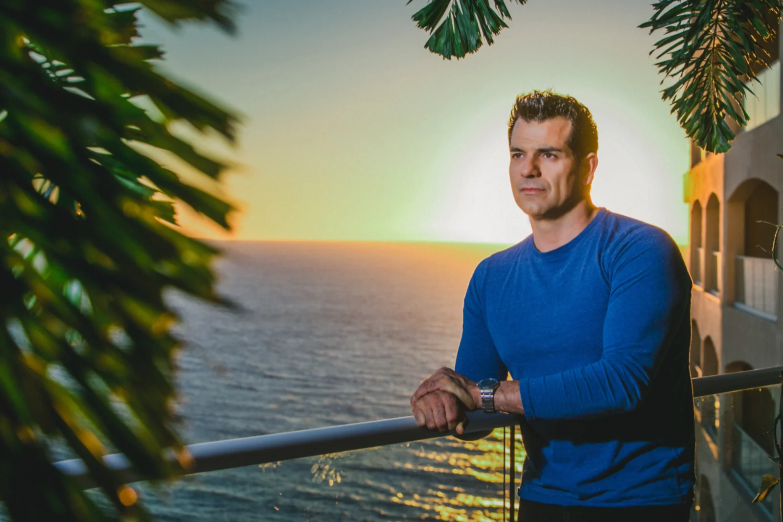 Johnny Tabaie, founder of Holistic Sanctuary, on an oceanfront balcony at sunset