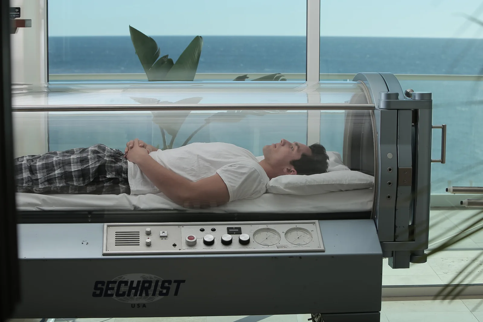 Guest resting inside a hyperbaric oxygen chamber with an ocean view at Holistic Sanctuary