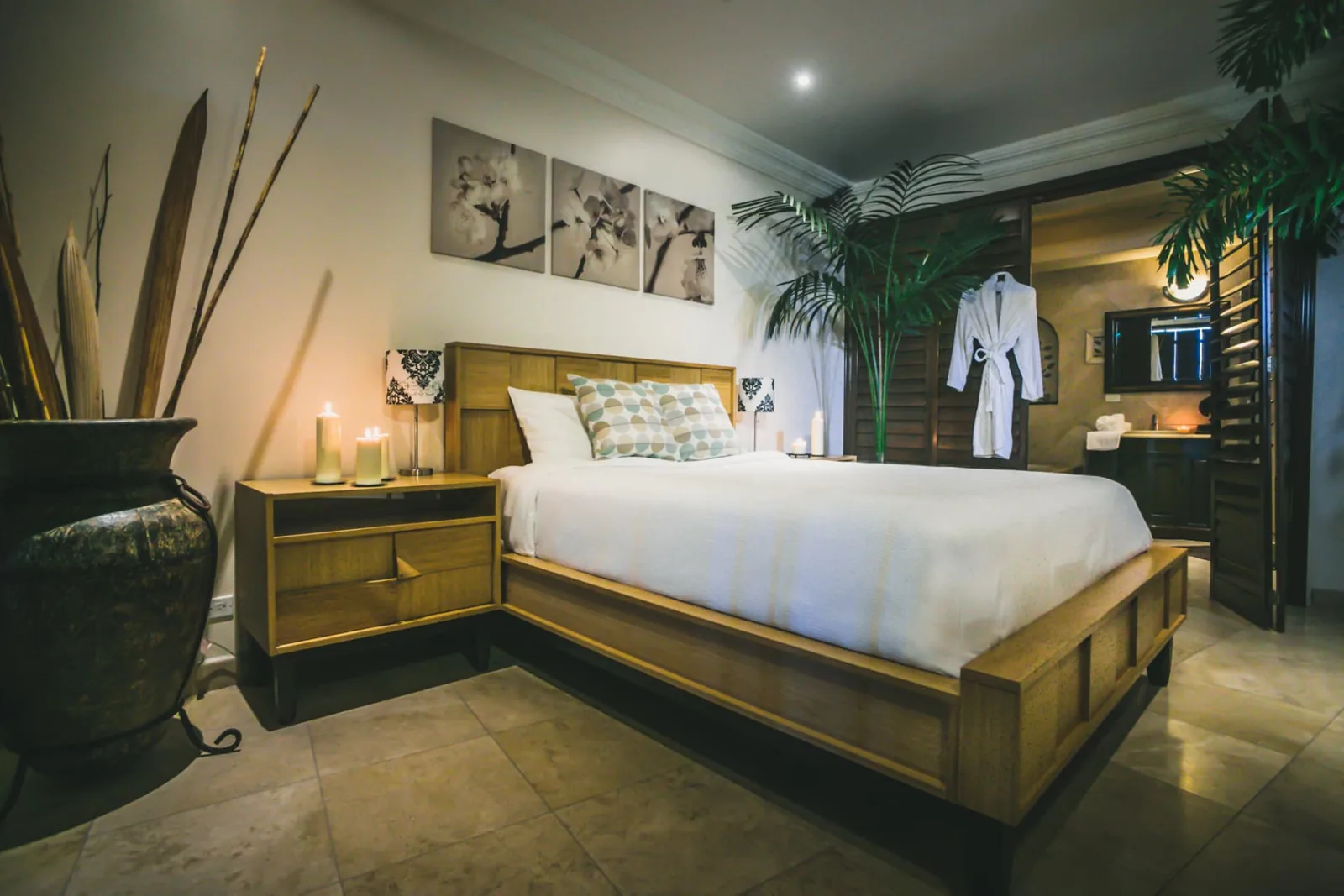 Candlelit private master suite at Holistic Sanctuary with a made bed, robe and plants