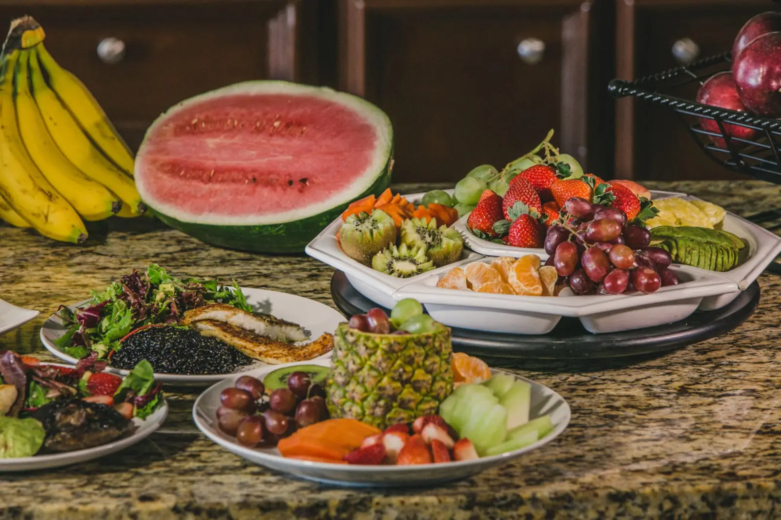 Plates of organic fruit, salad and prepared food on a kitchen counter
