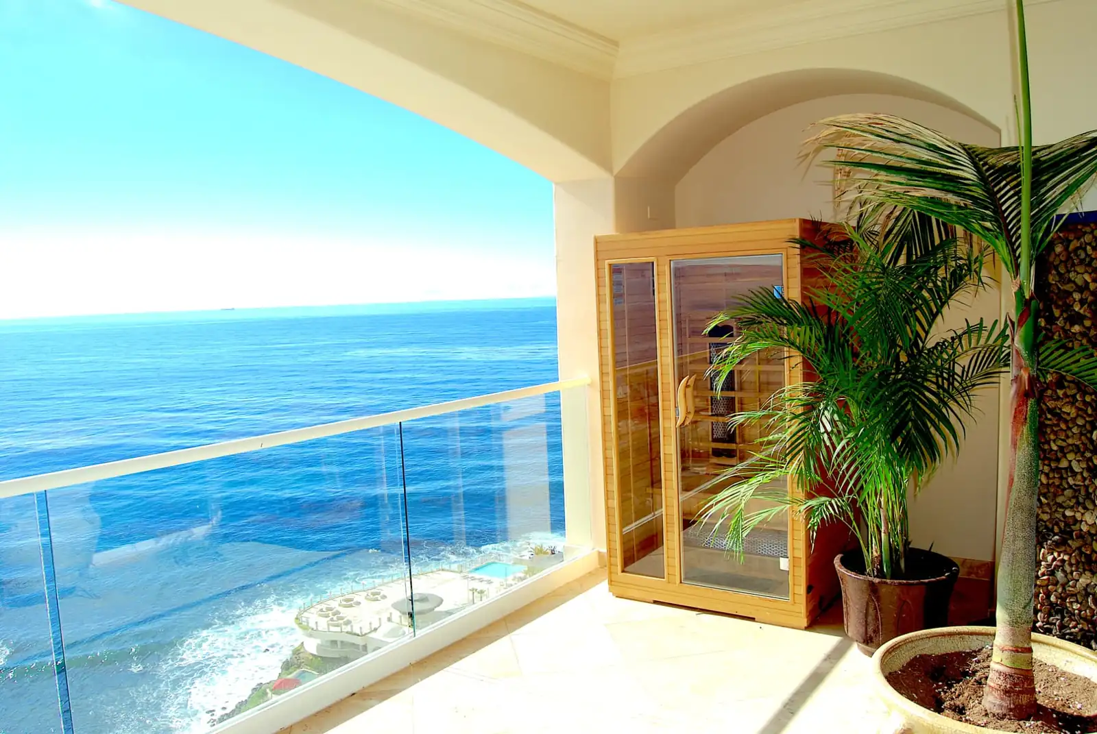 Infrared sauna cabin on a sunlit terrace overlooking the ocean at Holistic Sanctuary