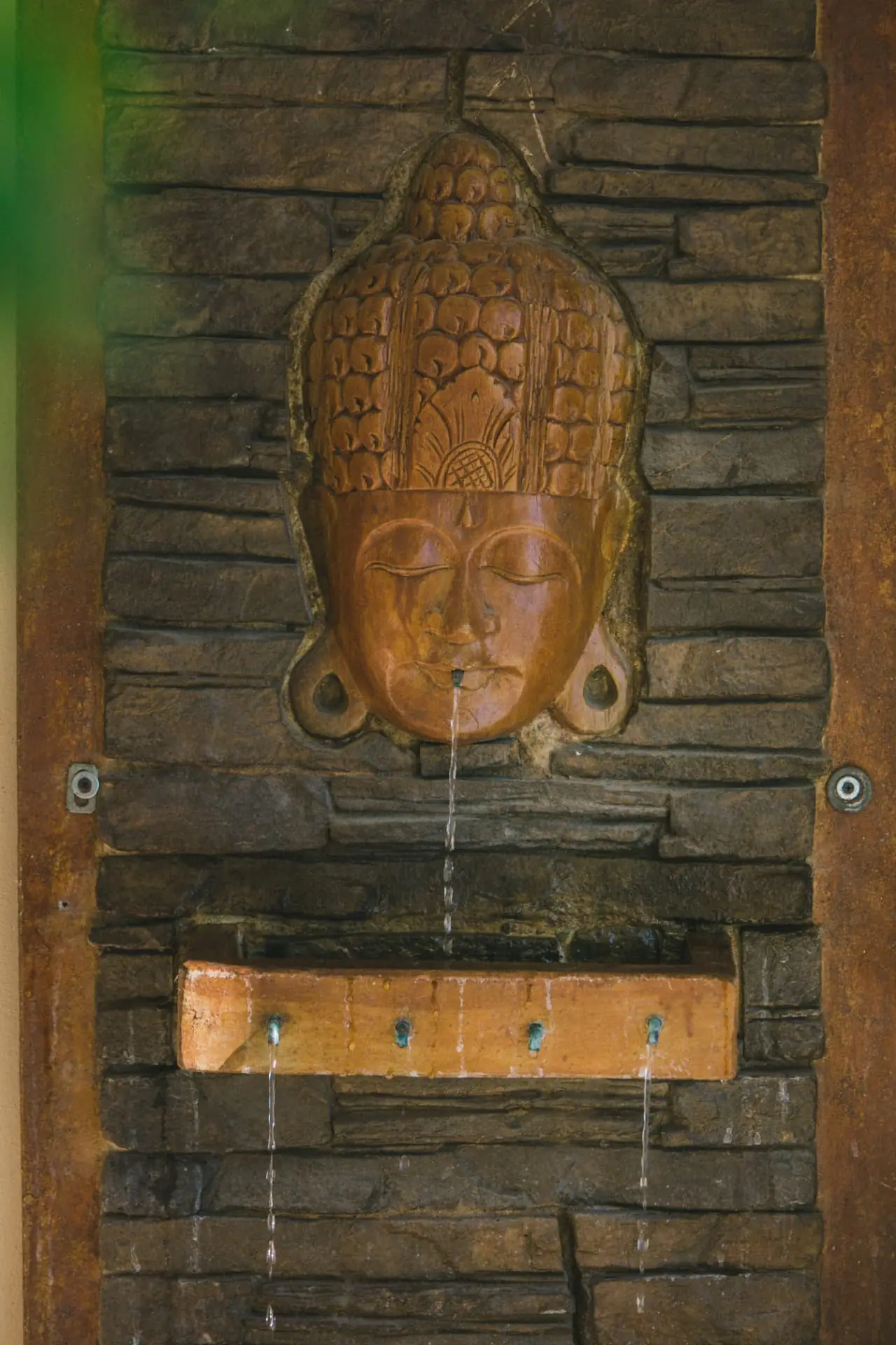 Carved stone water fountain in a quiet corner of the Holistic Sanctuary grounds